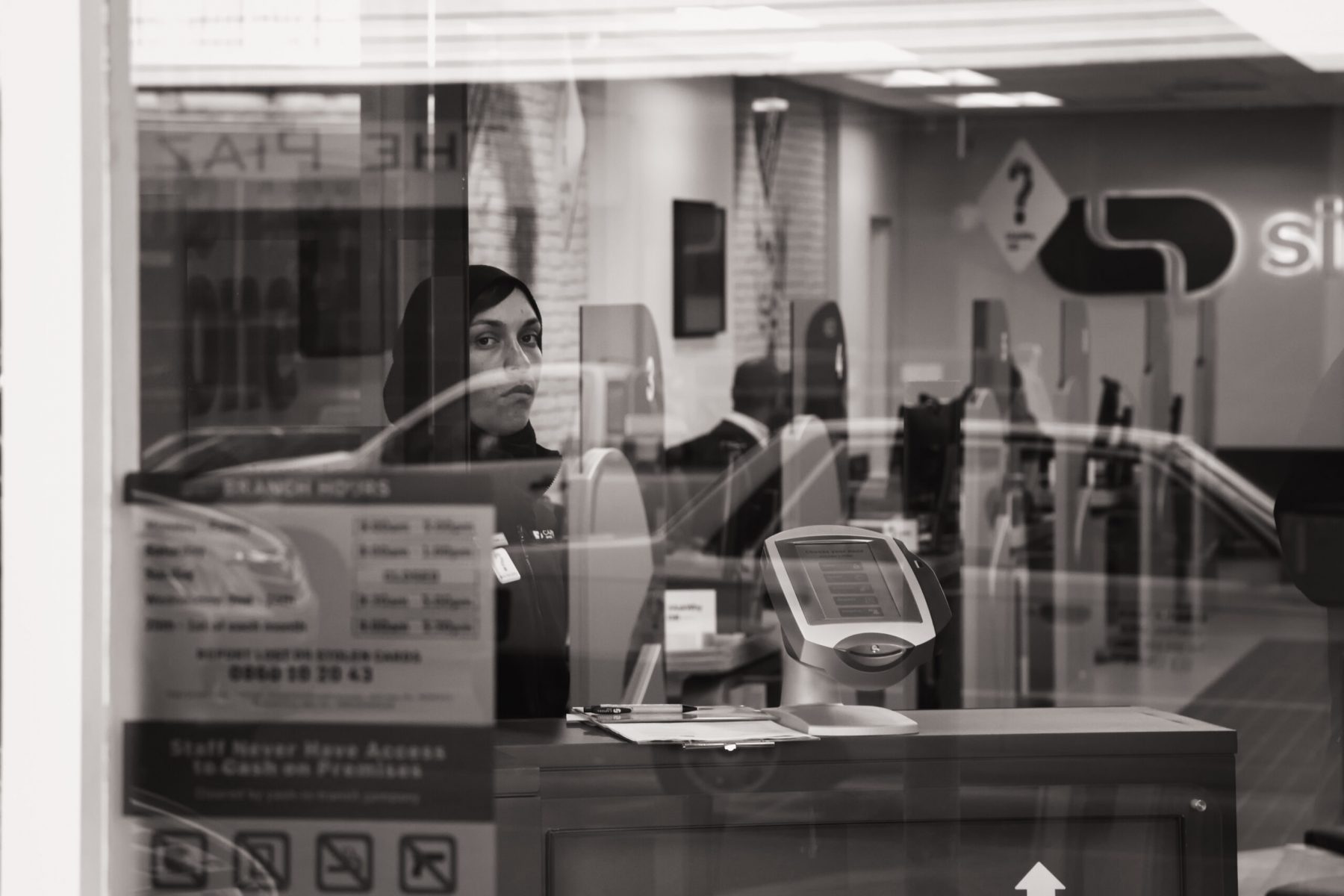 A woman looks through reflections in a window